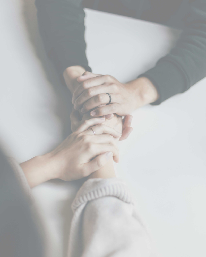 Zwei Menschen halten sich über einen Tisch hinweg an den Händen.