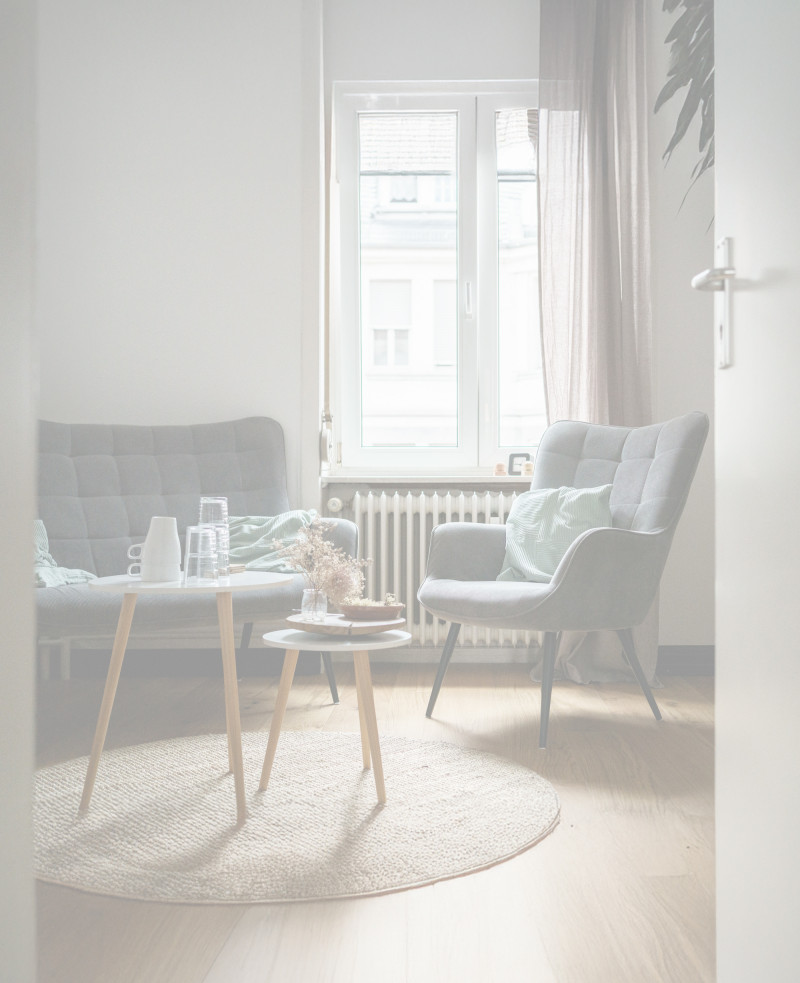 Zwei Sessel mit Beistelltischen in einem ruhigen, hellen Raum.