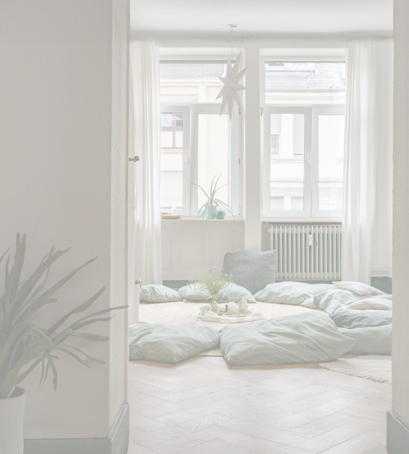 Heller Raum mit Sitzkissen auf dem Boden und sanftem Tageslicht – ein stiller, vorbereiteter Ort für Begegnung und Austausch.